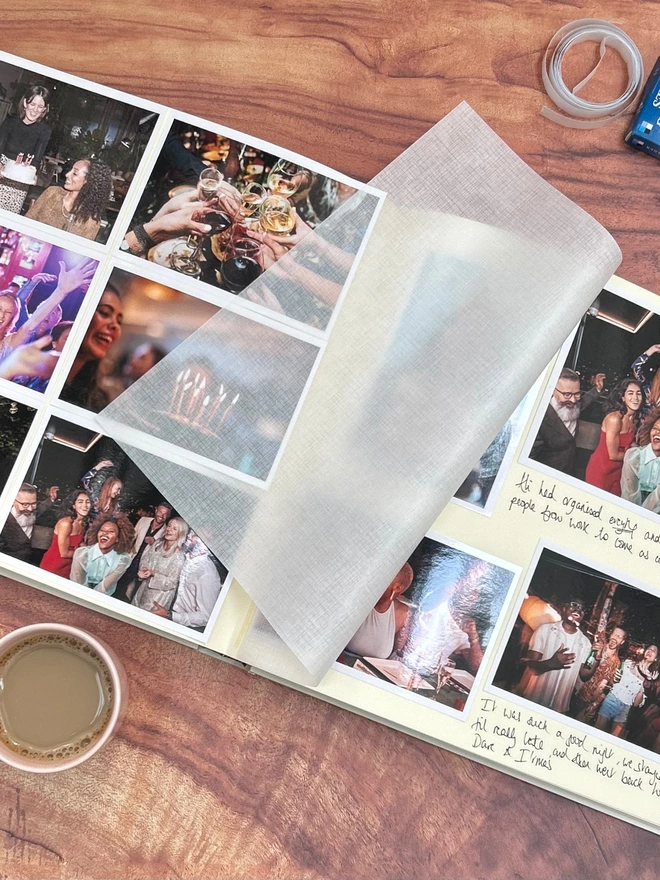 A large luxurious photo album is lying open on a coffee table with lots of photos of friends inside. 