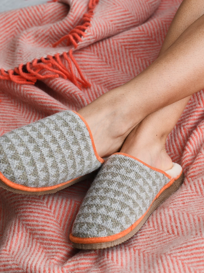 Lambswool & Sheepskin Slippers, a pair of colourful lambswool and sheepskin slippers sitting modelled on a colourful blanket 