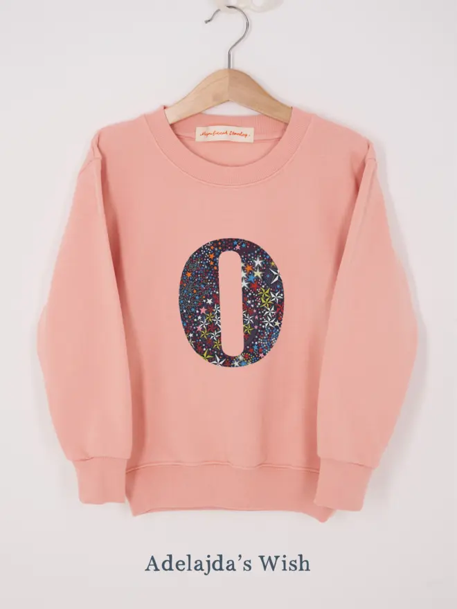 a personalised dusty pink sweatshirt with her initial sewn on the front in star liberty print 