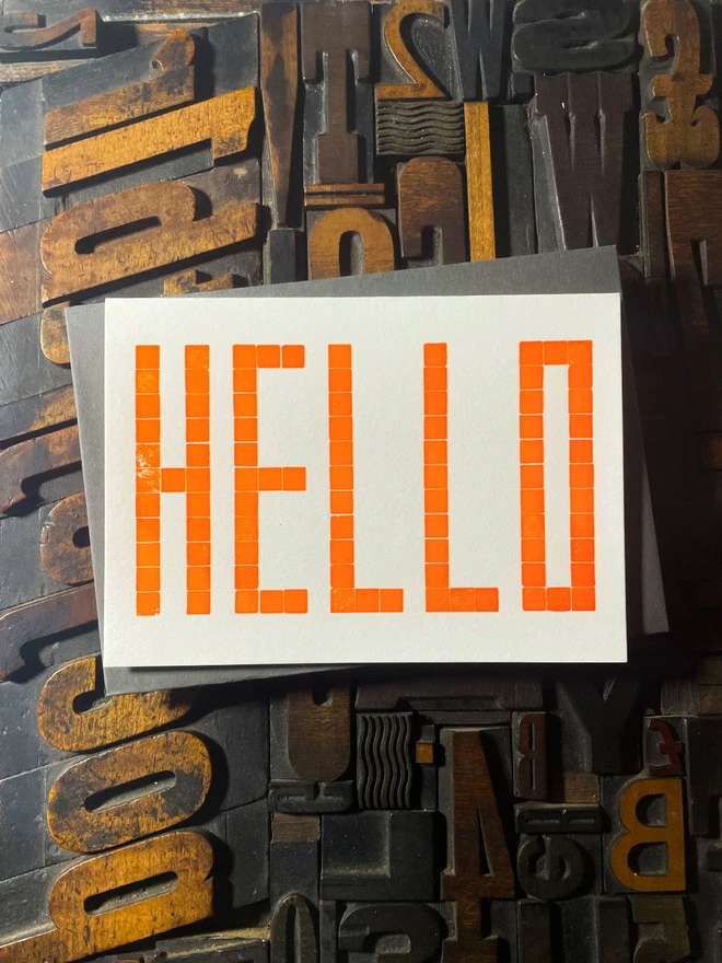 Letterpress HELLO postcard printed from a grid of square wooden type blocks in fluorescent yellow ink, deeply impressed on thick 350gsm Colorplan Pristine White card.