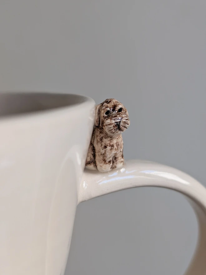 brown cockapoo mug with tiny miniature dog sitting on the white cup handle