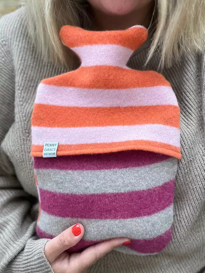 colourful stripy hot water bottle cover held in hands