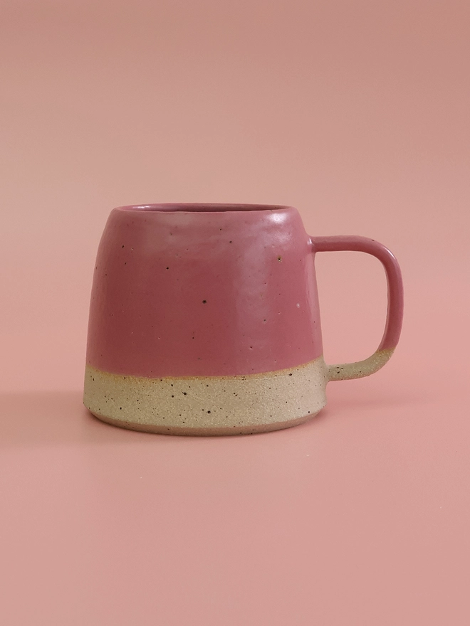 bright pink ceramic mug sits on a pink backdrop