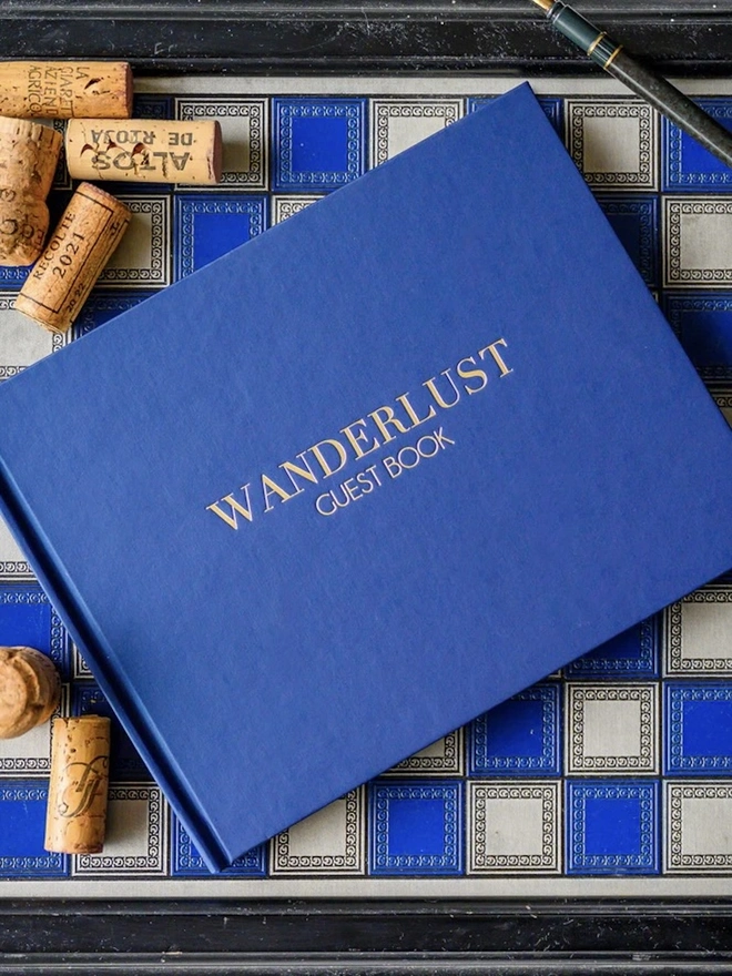 Personalised Luxury Guest Book For A Home, positioned above a blue chess board. 
