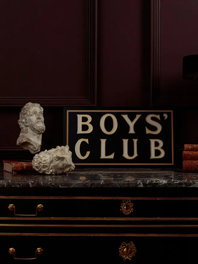 boys club hand painted sign. sign propped up on a mantelpiece.