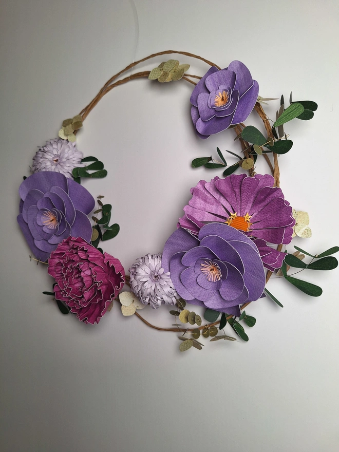 Side view of a handmade paper sculpture of a purple flower wreath 