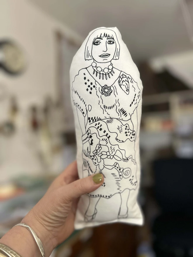 A black and white fabric cushion featuring an illustration of Zandra Rhodes.