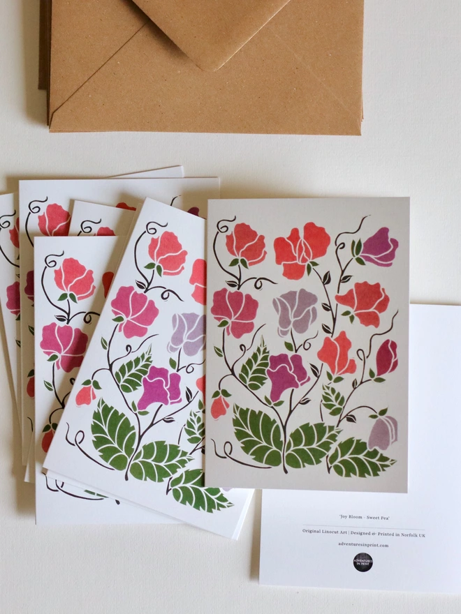 Set of 8 hand-carved botanical notecards featuring sweet peas. A6 linocut print greeting cards in pink and lilac, displayed with kraft envelopes. Cottagecore stationery on recycled cardstock.
