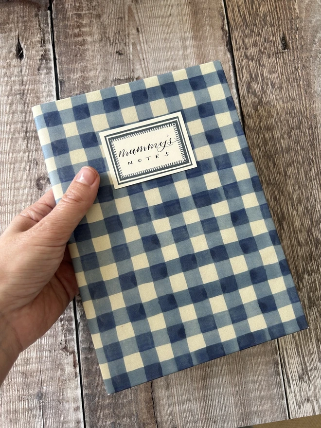 Personalised Mummy's notes gingham notebook held in hand against wooden floorboards