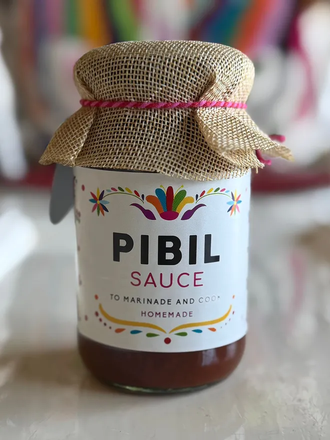 jar of sauce with white label reading 'pibil' and cloth lid covering
