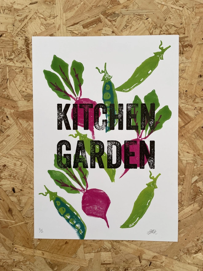 Hand-printed lino kitchen print featuring pea and beetroot illustrations on a wooden table.