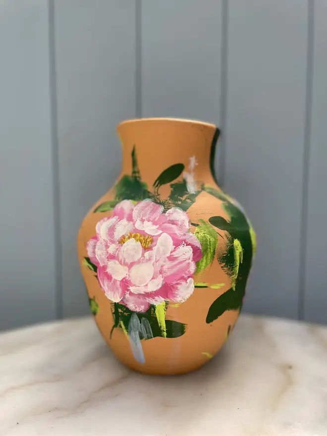 Unique hand-painted terracotta pot featuring pink peony on a terracotta background