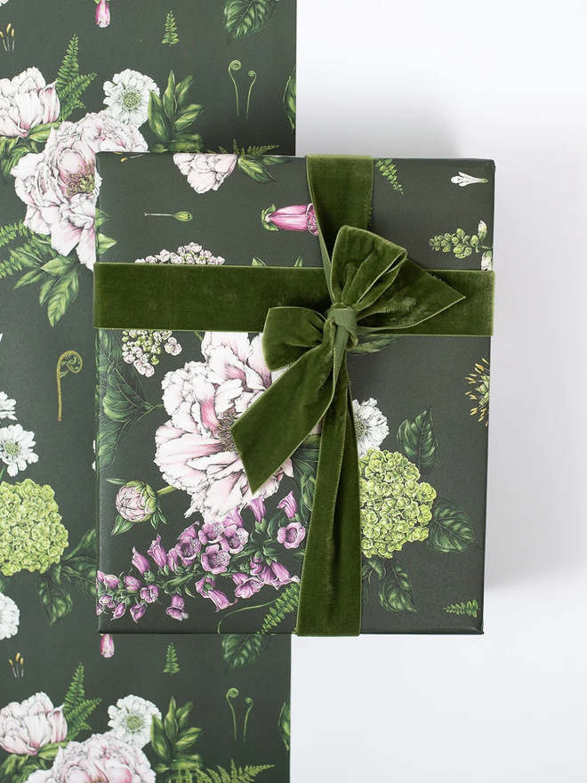 summer garden gift wrap sheet. a box wrapped in dark green illustrated floral gift wrap with a green ribbon.