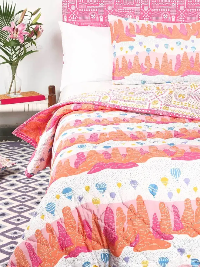 Evil Eye Flatweave Rug, a colourful rug in a living room. It is accompanied by other colourful household items. 