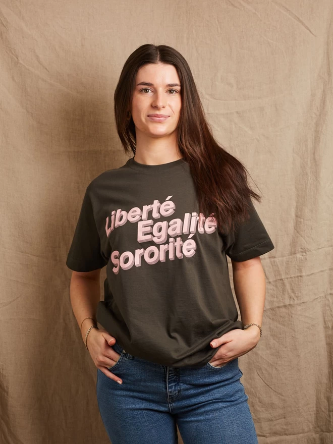 Model is wearing a charcoal grey cotton t-shirt with the slogan Liberté, Egalité, Sororité in pale pink written on the front