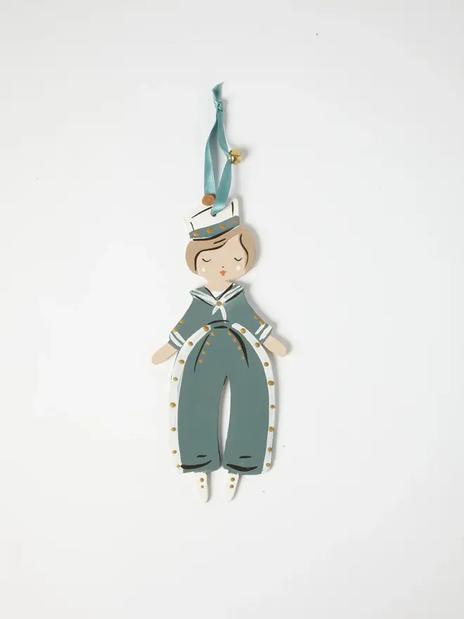 Sailor Heart Tree Dancer. wooden hanging sailor boy decoration with a white sailor hat, sage green and white jumpsuit with gold buttons, duck egg blue ribbon with a jingle bell, on a white background