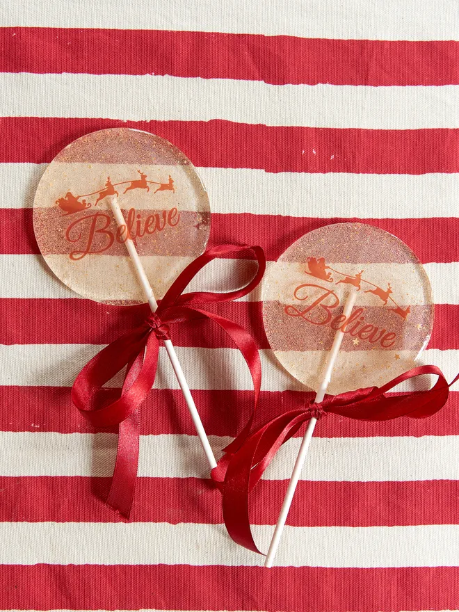 Large sparkly Believe Lollipop placed on a red striped tablecloth
