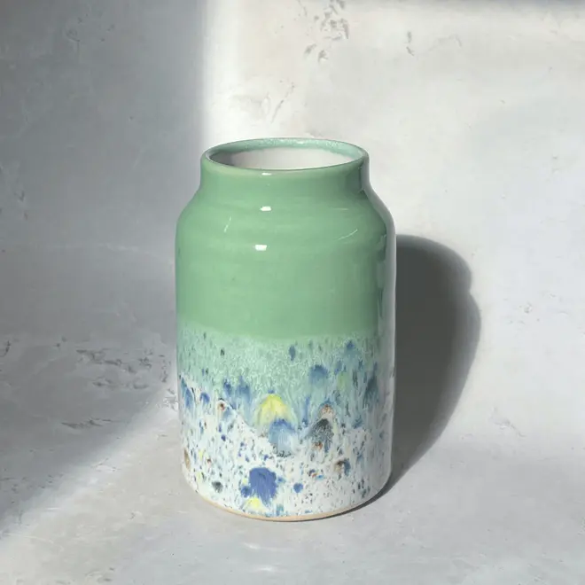 Shoreline Large Vase, a colourful vase placed on a stone surface in front of a plain backdrop. 