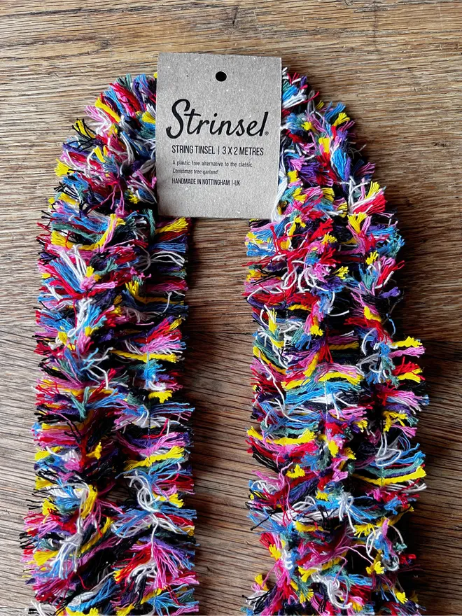 Multipack of Rainbow Strinsel string tinsel with kraft label on an oak table top