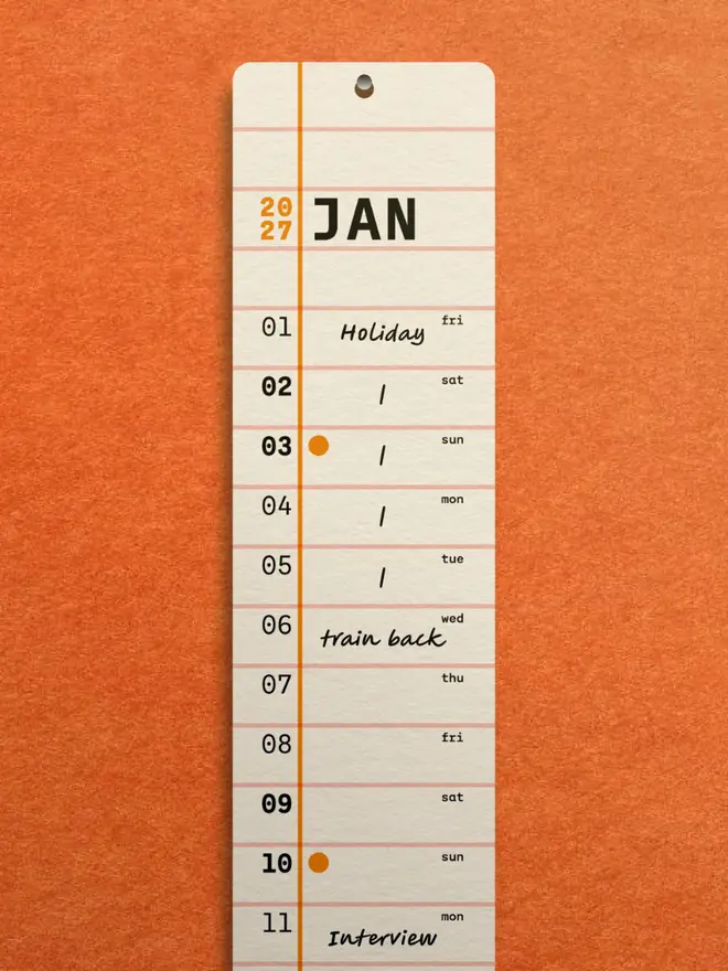 Squared: 2027 Monthly Wall Calendar, on an orange wall. 