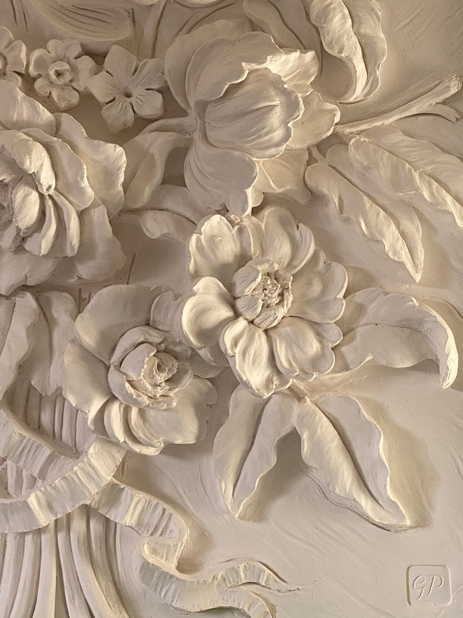 Detail of plaster sculpture with flower design with Dahlias and Roses in warm evening light