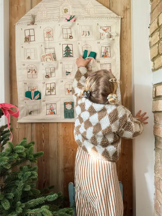 Fabric Christmas House Advent Calendar, with a little girl putting in a present. 