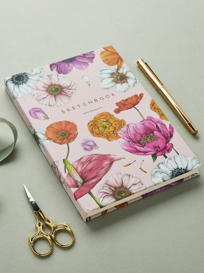 'Floral Brights' A5 Hardback Sketchbook. a pink floral sketchbook photographed on a plain grey background.