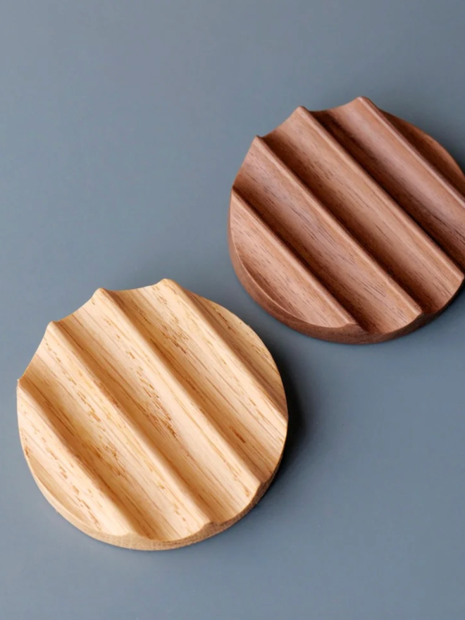 Tani Wooden Pen Rest. Both colour variants of the rest are shown side by side. We can see the Walnut variant is considerably darker than its Oak counterpart.