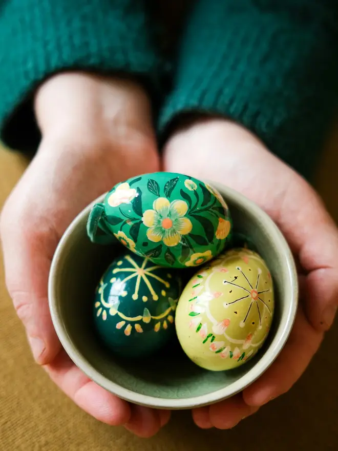 Group shot of hand painted decorative eggs in a bowl on a wooden table