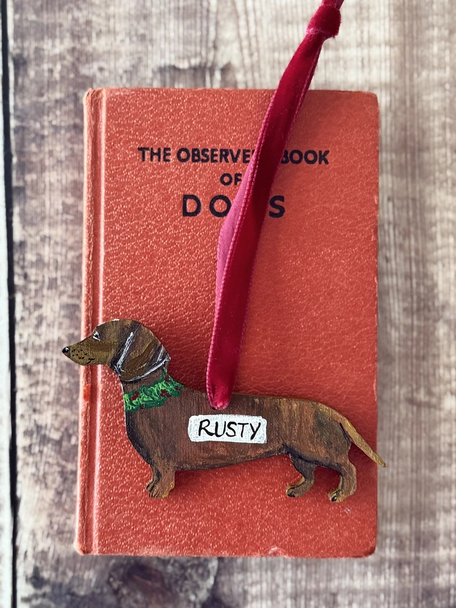 Smooth - haired  tan coloured Wooden dachshund Christmas Decorations strung with red velvet ribbon and the name rusty