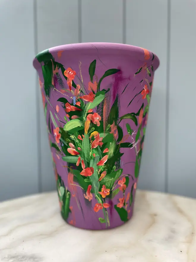 Unique hand-painted terracotta pot featuring twizzle coral flowers on a purple background