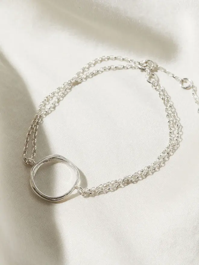 Silver Organic Circle Bracelet draped on silk material
