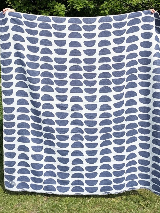 Organic Cotton Throw, a person holding the throw in front of them outside. 