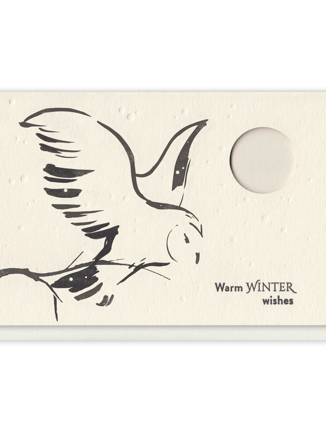 Letterpress greeting card with black, simple design of a snowy owl in flight against a moon backdrop cut-out from the paper.