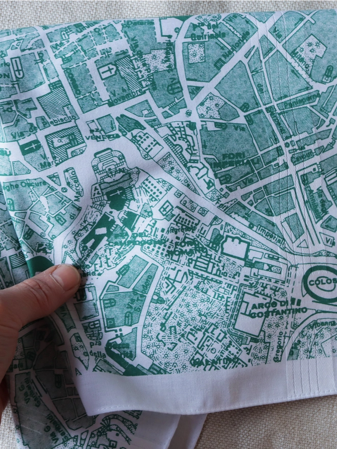 A Mr.PS Rome vintage map handkerchief screenprinted in sage green held with a white hand