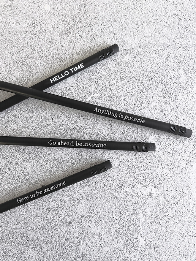 Four black pencils with motivational quotes on a grey background