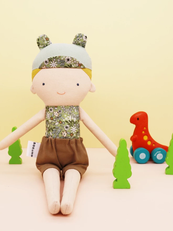blonde boy doll with green floral top and brown shorts 