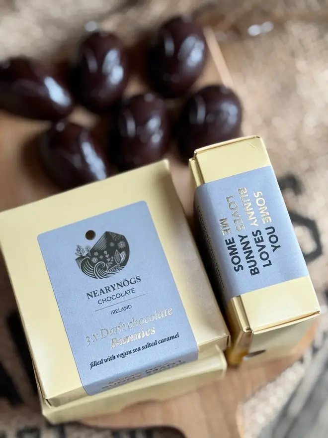 Chocolate Caramel Filled Bunnies 60% (Box Of 3), a stack of chocolate boxes accompanied by chocolate rabbits next to them. 