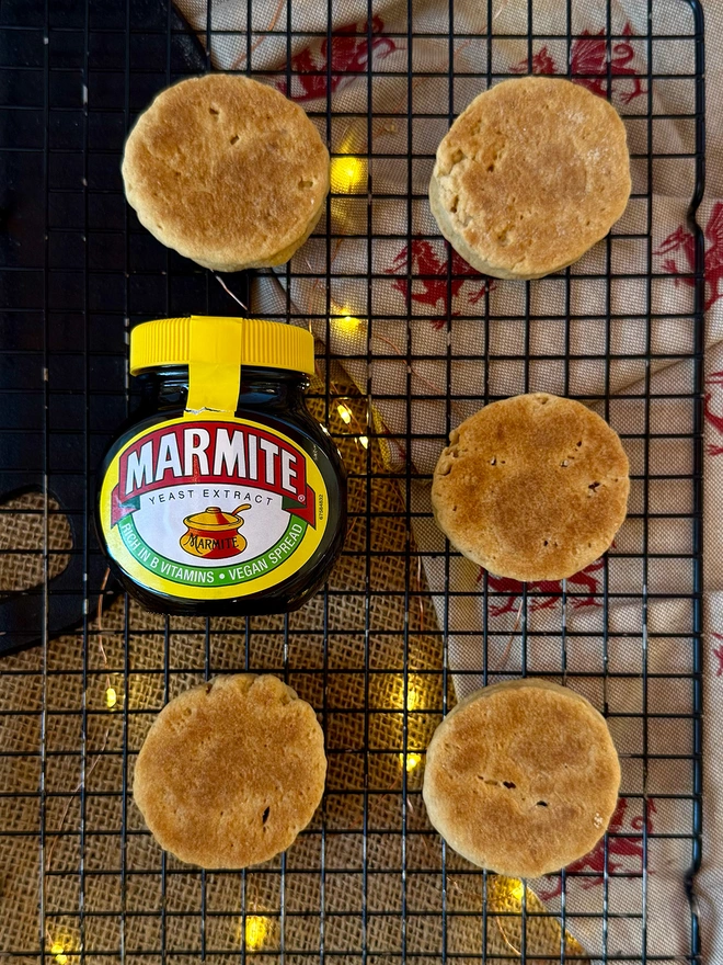 5 Marmite and Cheese Welsh Cakes neatly displayed on a cooling rack next to a jar of marmite