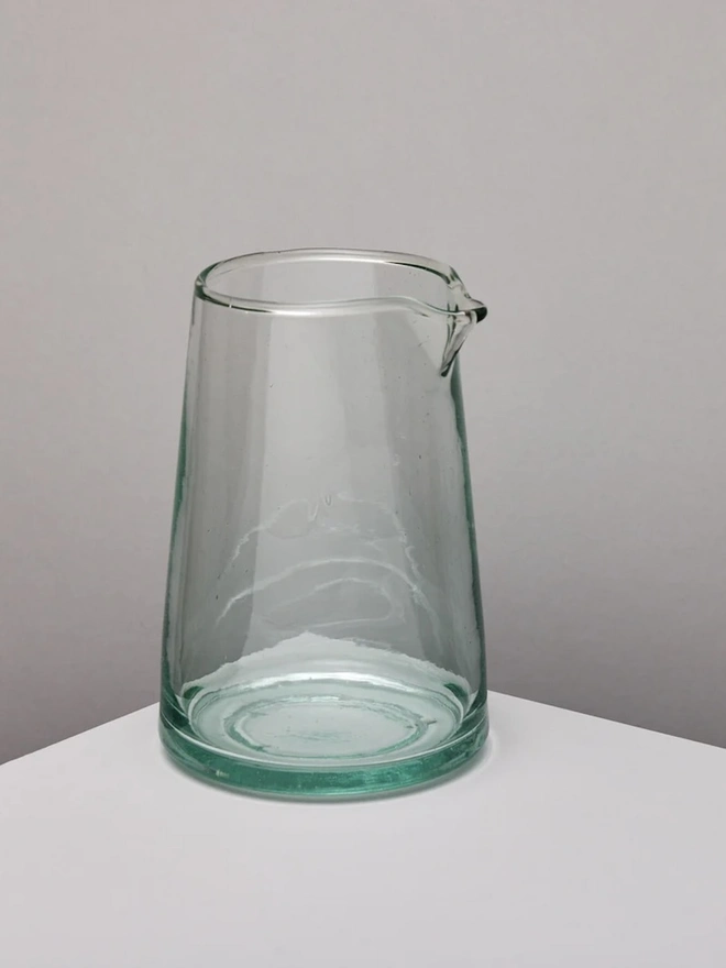 Tapered Carafe, a glass carafe sitting on a white counter top against a grey backdrop. 
