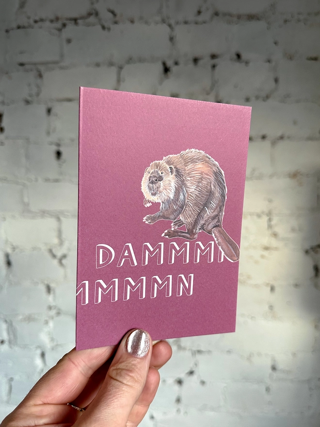 a pinky purple greetings card featuring an illustration of a beaver with the text “dammmmmn”