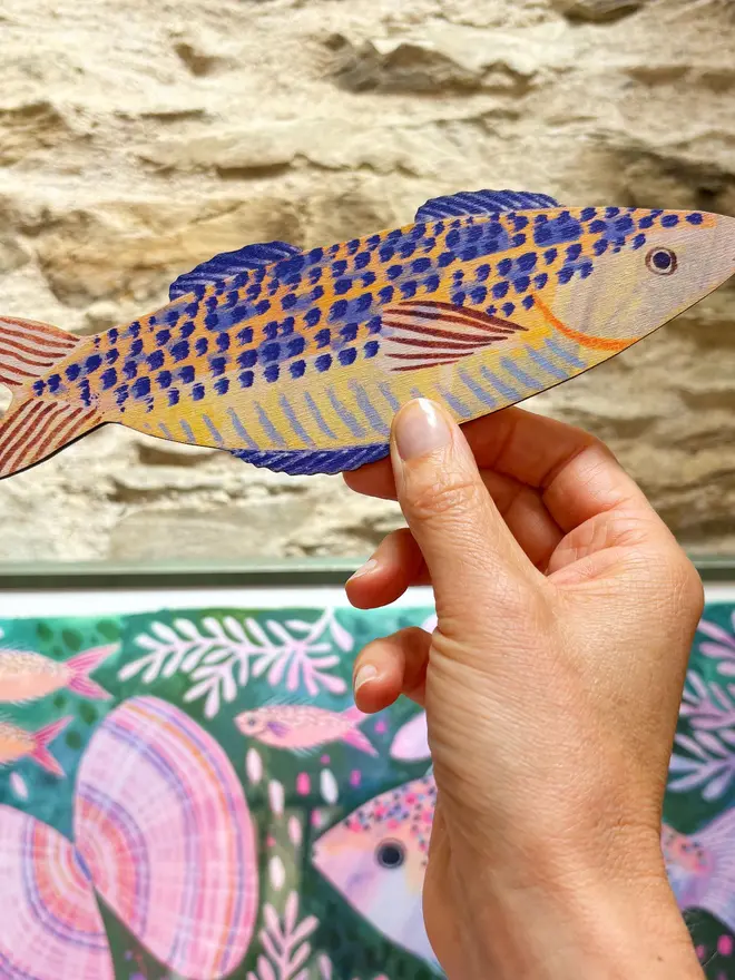 blue wooden mackerel wall decorations. wooden mackerel decorations held against brick wall.