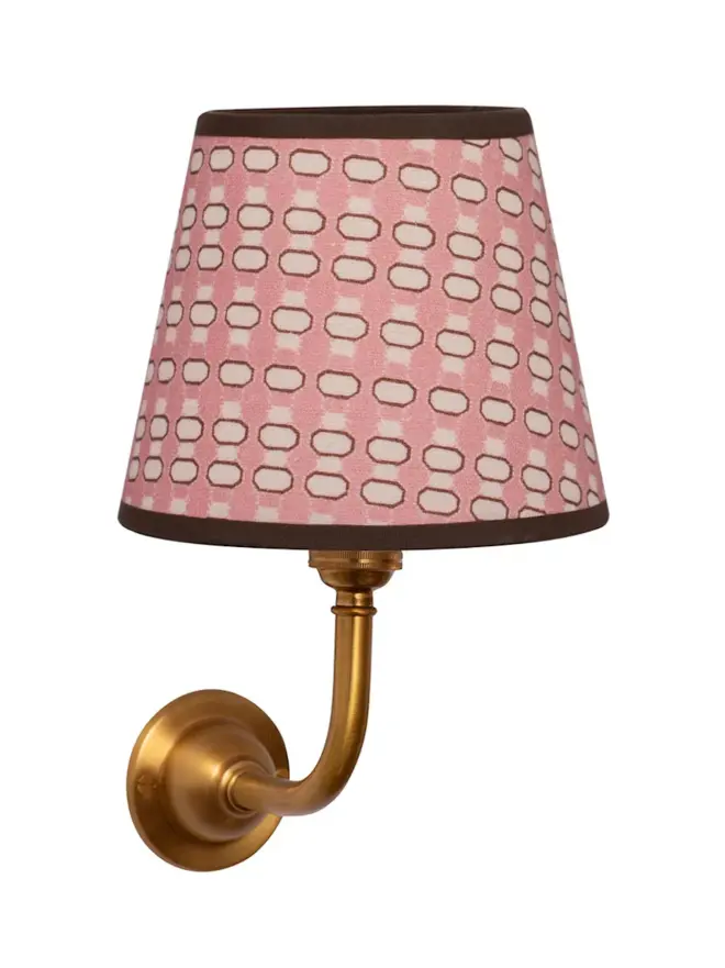 pink lalli patterned lampshade on golden sconce, on white background