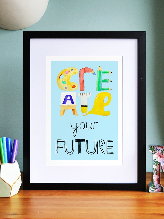 Art print saying 'Create your future' in a black frame in a child's room