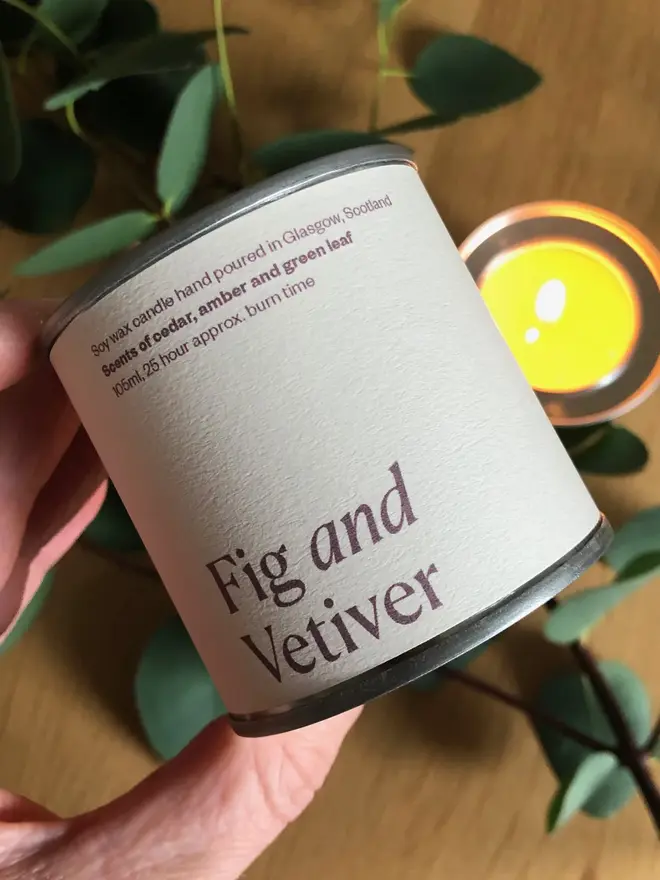 Fig & Vetiver Candle against a plant and wooden background. 