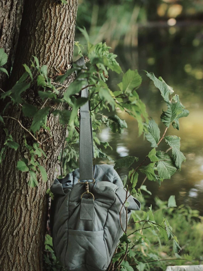 A changing bag in flint colour hanging on a tree