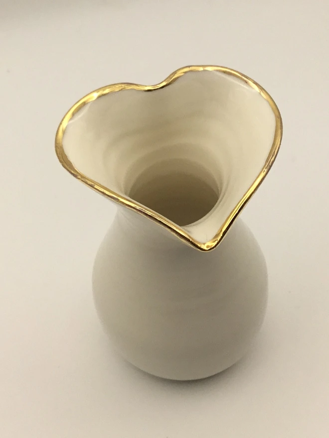 porcelain gold rim heart shaped vase. a white vase with a gold rim, heart shape opening and round base.