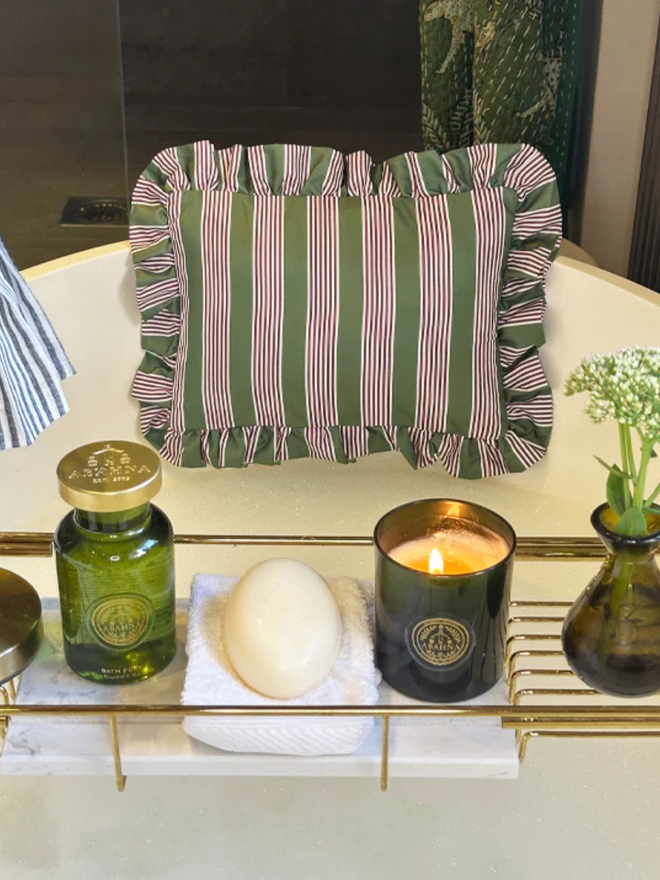 luxury frilled bath pillow. a pink and green striped frilled bath pillow affixed to a bath with candles.