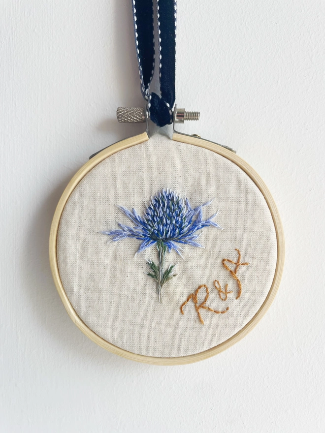 Embroidery hoop with a sprig of sea holly and the initials R&A