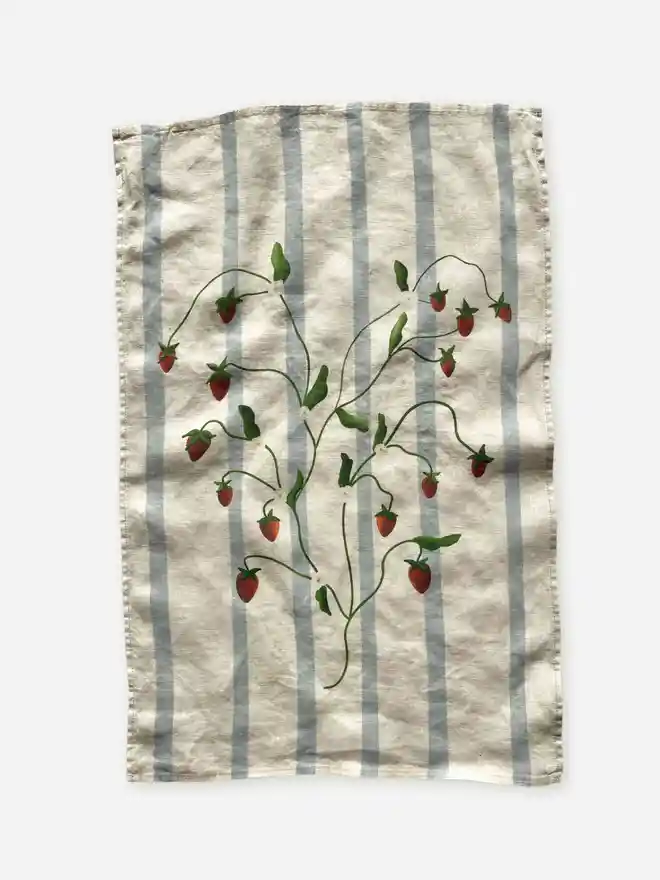 'Strawberry Vines' Linen Tea Towel, a person holding a tea towel with a strawberry motif on it. 